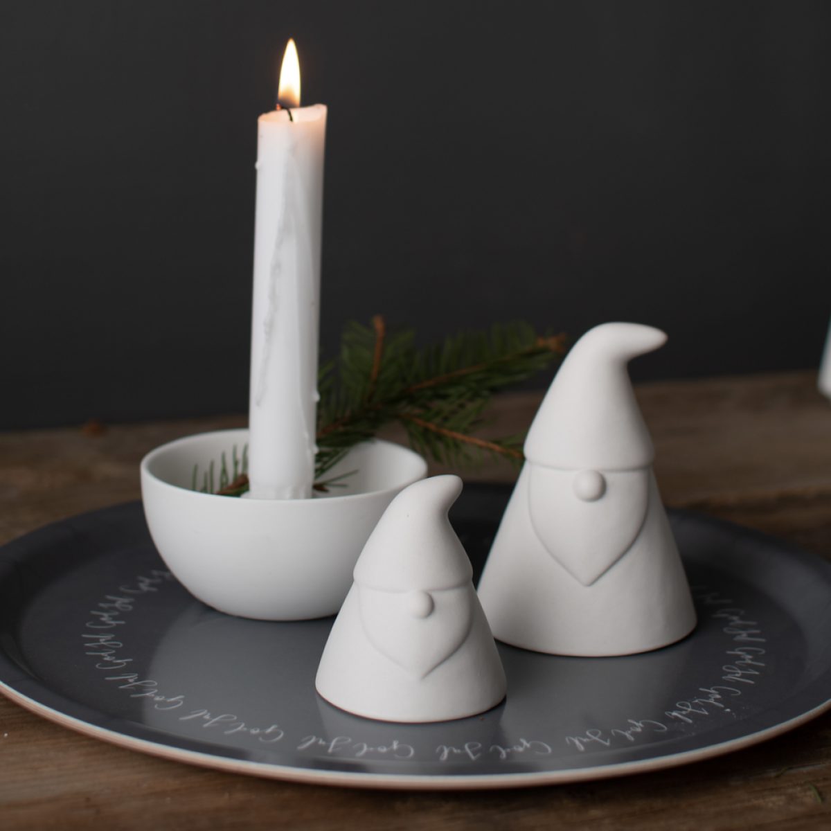 Zwei weiße Glasweihnachtsmänner und weißer runder Kerzenhalter