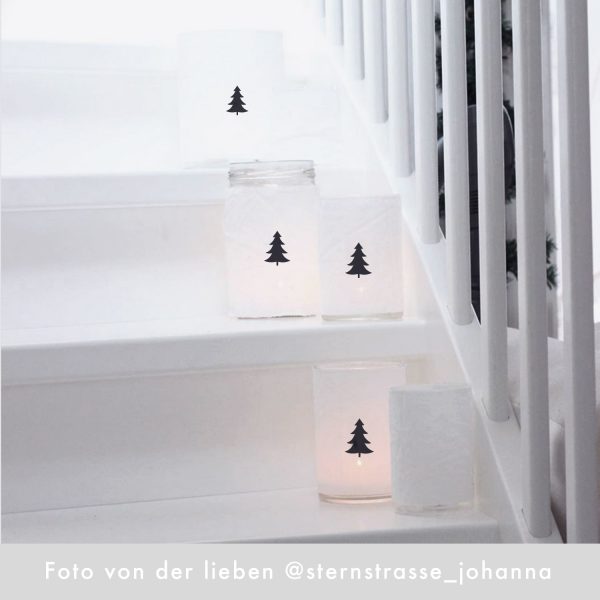 Weiße Kerzenteelichter mit schwarzem Weihnachtsbaum auf einer weißen Treppe